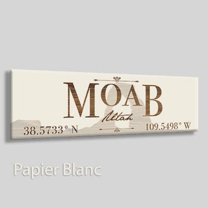 May include: A beige canvas print with the word "MOAB" in brown text with a silhouette of a mountain arch in the background. The text "Utah" is below the word "MOAB" and the coordinates "38.5733° N 109.5498° W" are below the silhouette.