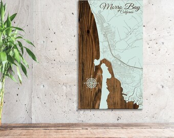 May include: A wooden map of Morro Bay, California, with a compass rose and the text "Morro Bay, California". The map is on a light brown wooden background.