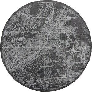 May include: A black slate coaster with a white engraved map of Riverside, California. The text "Riverside, California" is also engraved on the coaster.