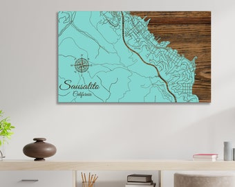 May include: A teal blue and brown wood map of Sausalito, California. The map features a compass rose and the text "Sausalito, California".