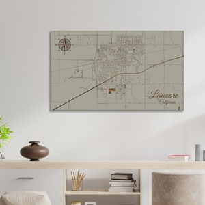 May include: A wood-mounted map of Lemoore, California, with a compass rose in the top left corner. The map is printed on a light gray background and features brown lines for streets and roads.