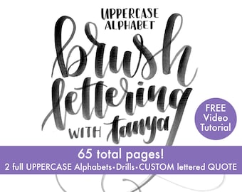 Könnte beinhalten: Schwarzweißes Bild der Wörter "brush lettering with Tanya" in handschriftlicher Form. Der Text ist in einer großen Schriftart und zentriert auf der Seite. Die Wörter "UPPERCASE ALPHABET" sind in einer kleineren Schriftart über dem Haupttext geschrieben. Die Wörter "65 total pages!" sind in einer kleineren Schriftart unter dem Haupttext geschrieben. Die Wörter "2 full UPPERCASE Alphabets. Drills. CUSTOM lettered QUOTE" sind in einer kleineren Schriftart unter den Wörtern "65 total pages!" geschrieben. Die Wörter "FREE Video Tutorial" sind in einer kleineren Schriftart in einem Kreis in der unteren rechten Ecke des Bildes geschrieben.
