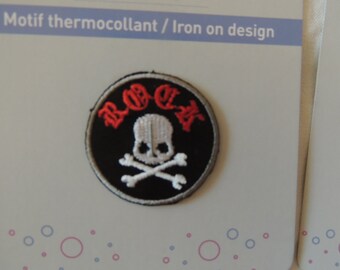 May include: A black and white iron-on patch with a skull and crossbones design. The word "BOB" is written in red above the skull. The patch is on a white background with small blue and pink circles.