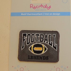 Könnte beinhalten: Bügeleisen-Aufnäher mit einem braunen Fußball mit weißen Nähten und einem gelben Streifen. Der Text "FOOTBALL LEGENDS" ist in weißer und schwarzer Schrift.