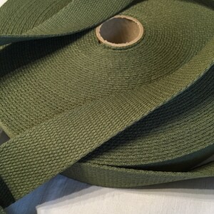 May include: A roll of olive green cotton webbing, a type of heavy-duty fabric used for straps and belts.
