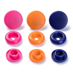 Peut inclure: Neuf boutons-pression en plastique de trois couleurs : rose, orange et bleu. Les boutons sont disposés en trois rangées de trois, la rangée du haut montrant les boutons dans leur intégralité et les deux rangées du bas montrant les boutons de côté.