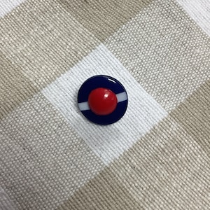 Könnte beinhalten: Ein blauer und weißer Knopf mit roter Mitte. Der Knopf hat einen weißen Streifen am Rand.