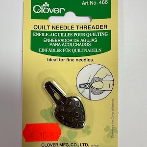 May include: A Clover quilt needle threader on a yellow and green card. The threader is dark metal with a decorative design. Text on the card includes "Quilt Needle Threader" and "Ideal for fine needles."