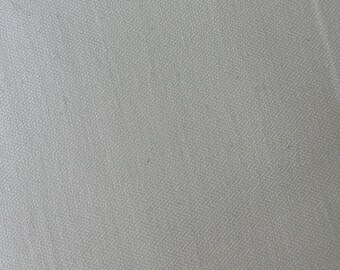 May include: Close-up of a light gray fabric with a subtle herringbone weave pattern. The fabric has a soft, textured appearance, with visible diagonal lines creating a visual texture. The overall tone is neutral and versatile.