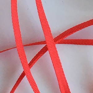 Puede incluir: Primer plano de una cinta naranja brillante, mostrando la textura de la tela.