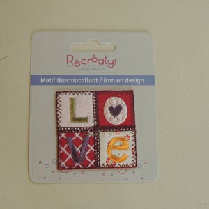Könnte beinhalten: Ein roter, weißer und goldener Bügelaufkleber mit der Aufschrift "LOVE" im Patchwork-Stil. Der Aufkleber befindet sich auf einer weißen Karte mit dem Text "Récréatys Loisirs Créatifs Motif thermocollant / Iron on design".