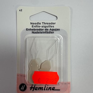 May include: A package of two needle threaders. The package includes the text "Needle Threader Enfile-aiguilles Enhebrador de Agujas Nadeleinfädler". The brand name "Hemline" is also visible. The threaders are in a clear plastic package.