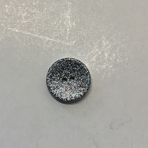 Può includere: Un bottone argentato con glitter e due fori.