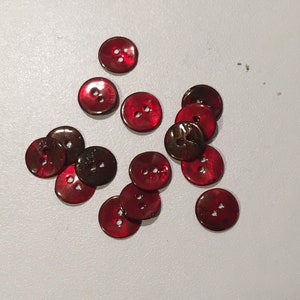 May include: A group of 12 red and brown iridescent buttons with two holes each.