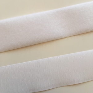 Peut inclure: Deux bandes de ruban adhésif auto-agrippant blanc. La bande supérieure est duveteuse et la bande inférieure est lisse.