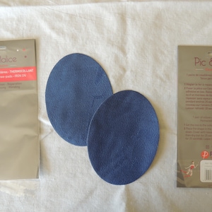 May include: Two blue iron-on elbow patches on a white surface with packaging that reads "Pic & Malice" and "THERMOCOLLANT".