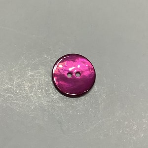 Peut inclure: Un bouton rose brillant avec deux trous.