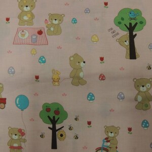 Peut inclure: Tissu rose avec un motif répété d'ours en peluche bruns, d'arbres, de champignons et d'abeilles. Le texte "One Two Three" est imprimé sur le tissu.