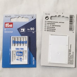 May include: Two packets of Prym sewing machine needles. One is blue and white, marked "Universal" and "No. 90 14". The other is white, with text in multiple languages. Both packets have the product code 152 412.