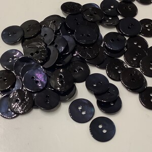 May include: A large pile of black, iridescent buttons with two holes each.