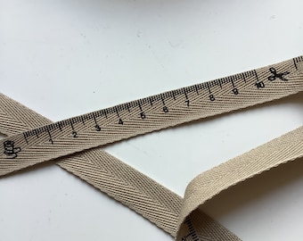 Woven ribbon, polyester, tape measure pattern, beige and black color, width 15 mm