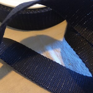 May include: A close-up of dark blue webbing with silver glitter woven into the fabric.