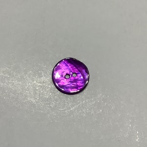 Peut inclure: Un bouton iridescent violet à deux trous avec une finition lisse et brillante.