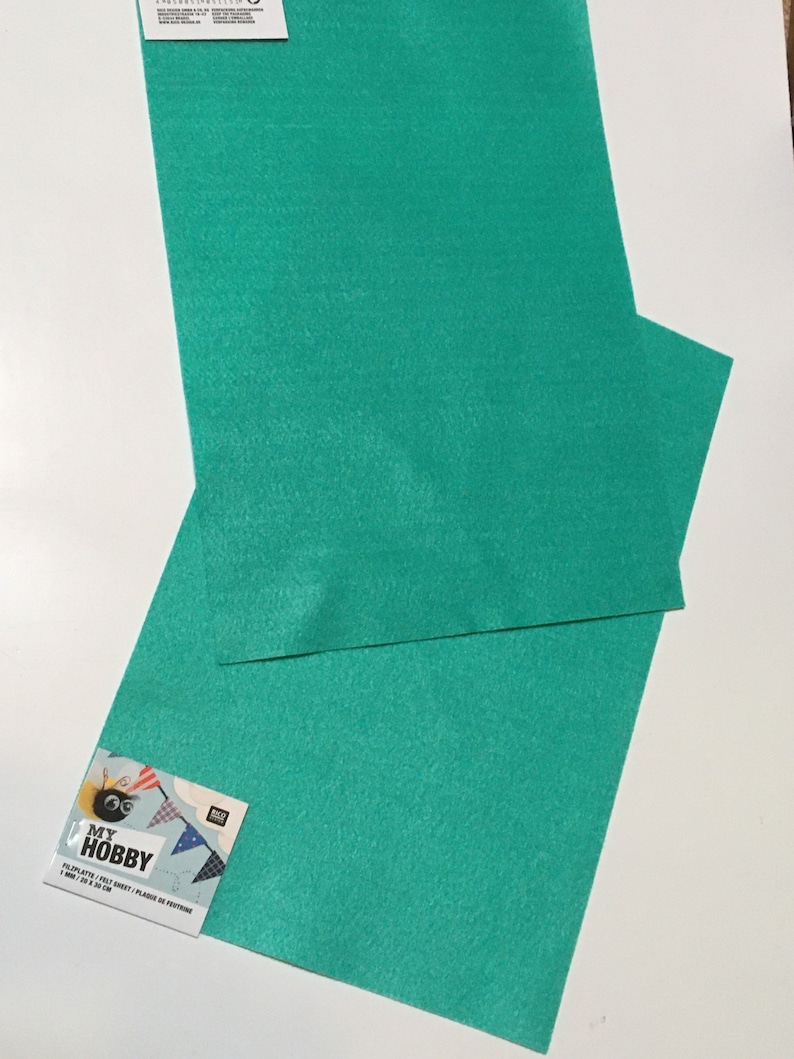 May include: Two sheets of teal felt, each measuring 23 x 30 cm. The felt is packaged with a label that reads "My Hobby Felt Sheet - Plaid de Feutre 1 mm - 9 x 12 in"