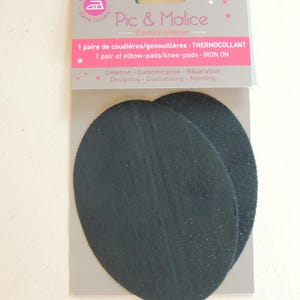 May include: Two black iron-on elbow or knee pads. The package says "1 pair of elbow-pads/knee-pads - IRON ON" and "Création - Customisation - Réparation Designing - Customising - Mending".