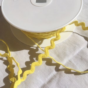 Puede incluir: Una bobina de ribete amarillo en zigzag con una etiqueta que dice "La s Article: 1171 Col: 81 25ml fabriqué en France 3589720682927"