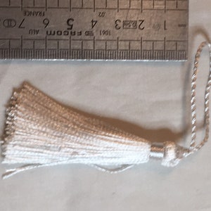 Può includere: Un fiocco bianco con un cordoncino argentato. Il fiocco è lungo circa 5 cm.