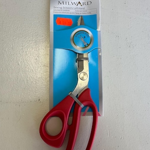 May include: Red-handled left-handed sewing scissors, 8 inches long, with stainless steel blades. The scissors are packaged on a blue and white card with the brand name "MILWARD" and product information.