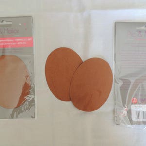Peut inclure: Deux patchs thermocollants de couleur marron pour réparer ou décorer les vêtements. Les patchs sont de forme ovale et sont emballés sur une carte blanche avec le texte "Pic & Malice" imprimé dessus.