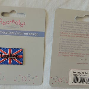 Op de afbeelding: Een witte kaart met een rood, wit en blauw strijk-op-patch van de Union Jack-vlag met het woord "London" in zwarte letters. De kaart bevat instructies voor het strijken van de patch op stof. De kaart bevat ook de productinformatie: Ref. 3882 TO Col.1, 100% polyester en een barcode.