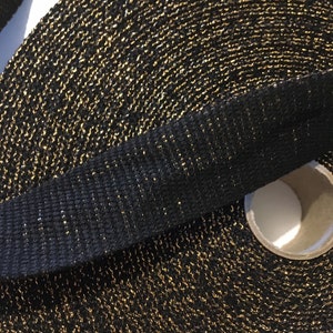 May include: A roll of black webbing with gold glitter woven into the fabric.