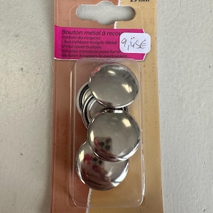 Peut inclure: Un paquet de trois ensembles de boutons de recouvrement en métal argenté brillant, chacun de 29 mm de diamètre. L'emballage contient du texte en plusieurs langues, dont "Bouton métal à recouvrir."