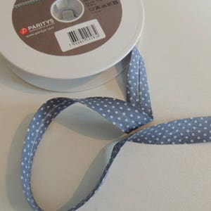 Peut inclure: Un rouleau de ruban bleu à pois blancs. Le ruban est sur une bobine blanche avec une étiquette qui dit "Parity's".
