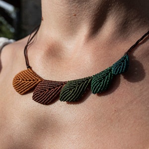 Peut inclure: Un collier avec une série de pendentifs en forme de feuille noués dans des tons de brun, orange et vert.