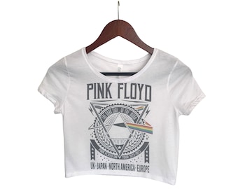 May include: White cropped t-shirt with a graphic print of Pink Floyd's "The Dark Side of the Moon" album cover. The graphic includes the band's name, the album title, and a stylized prism with a rainbow.
