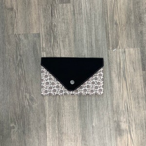May include: A black and white patterned envelope clutch with a black flap and a single button closure.