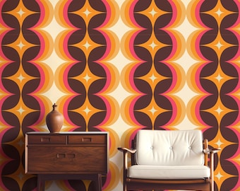 May include: A retro-style wallpaper with a repeating pattern of orange, pink, and brown circles and stars. The wallpaper is in a room with a wooden dresser and a white armchair.
