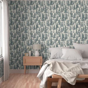 May include: Wallpaper featuring a repeating pattern of dark teal pine trees on a cream background. The design covers the wall behind a light wood nightstand with a white lamp and a small clock, and a bed with white bedding and pillows.