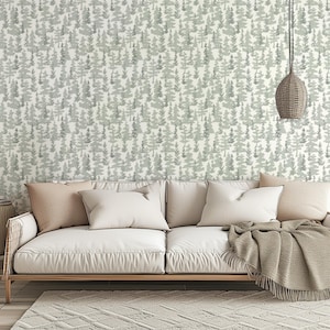 May include: A white couch with a light gray patterned wallpaper featuring a repeating design of trees. The couch has a light brown throw blanket draped over the back and two white pillows.