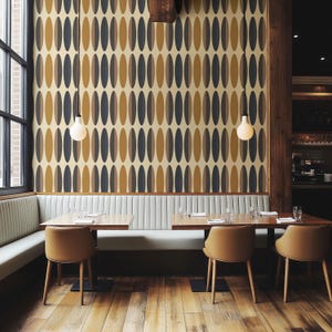 Può includere: Interno di un ristorante con una parete con un motivo ovale ripetuto in tonalità oro, marrone e grigio. La stanza ha pavimenti in legno, tavoli e sedie. Sono visibili anche una finestra e una panca bianca.