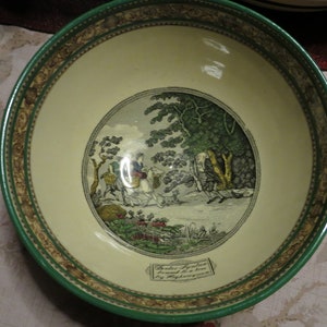 May include: A vintage green and gold bowl with a white interior. The bowl features a central image of a pastoral scene with figures on horseback and a tree. The text "Broder by a live stream and by a tree by Highmore" is printed on the bottom of the bowl.