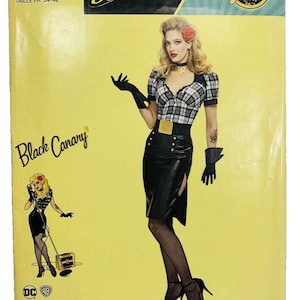 May include: A Simplicity sewing pattern featuring a DC Comics Bombshells design. The pattern includes a Black Canary costume with a plaid top, black skirt, and gloves. The pattern size is U.S. 6-14.