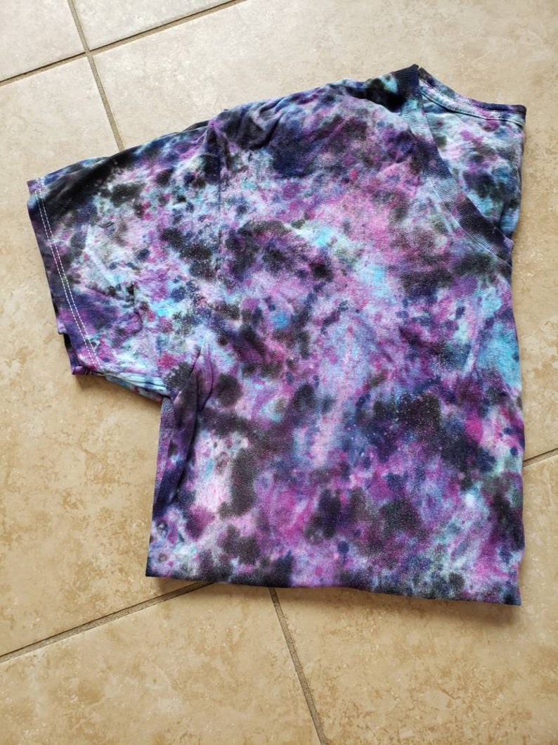 May include: A tie-dye t-shirt with a swirling pattern of black, purple, blue, and white.