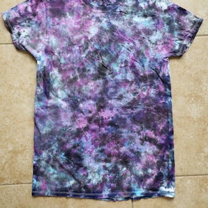 May include: A tie-dye t-shirt with a galaxy print in shades of purple, blue, and black.