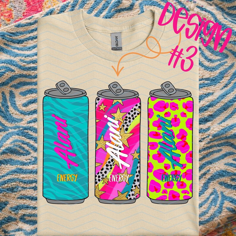 May include: A beige t-shirt featuring three colorful energy drink can designs. Each can has a different pattern: teal zebra stripes, pink and gold stars, and neon green leopard print. The name "Alani" is written on each can.
