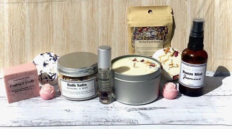 Op de afbeelding: Een spa-cadeauset met een verscheidenheid aan producten, waaronder badzout, een kaars, een kamerverspray, een badbom en een zeep. De producten zijn allemaal in witte en zilveren verpakkingen met bloemmotieven. De set is perfect voor ontspanning en verwennen.